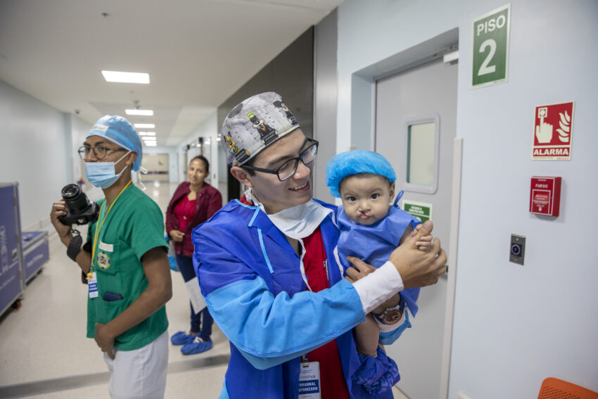 Medical professional comforts baby as they approach the operating room.