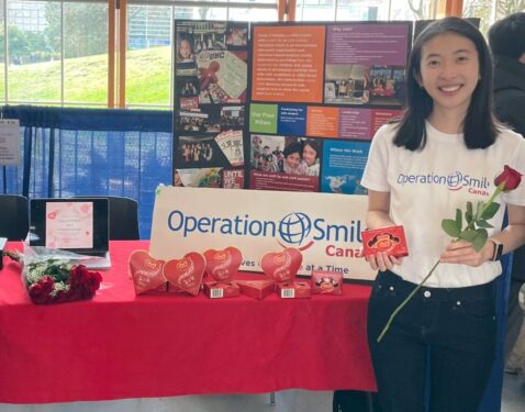 Student stands in front of a table where she is selling chocolates and roses.