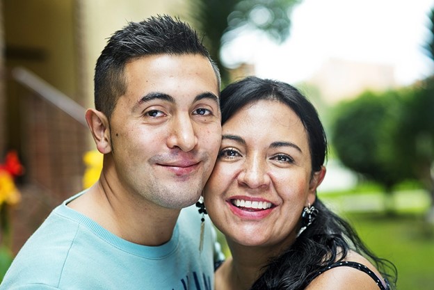 A young man and his mother pose together and smile
